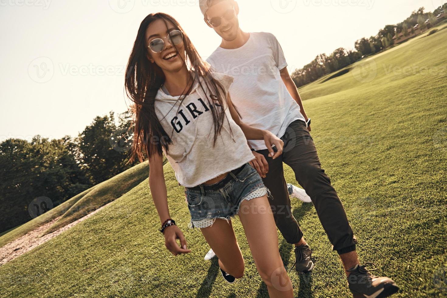 Happy to be around. Beautiful young couple in casual wear smiling while walking outdoors photo