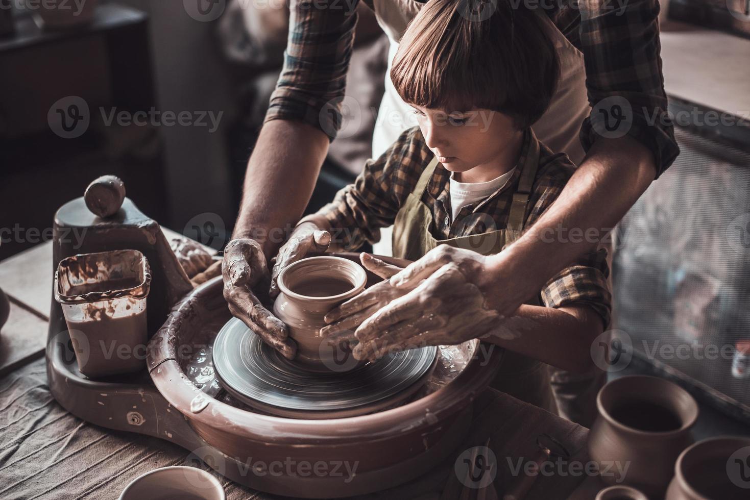 aprendiendo de alfarero confiado. primer plano de niño confiado haciendo vasija de cerámica en la clase de cerámica foto