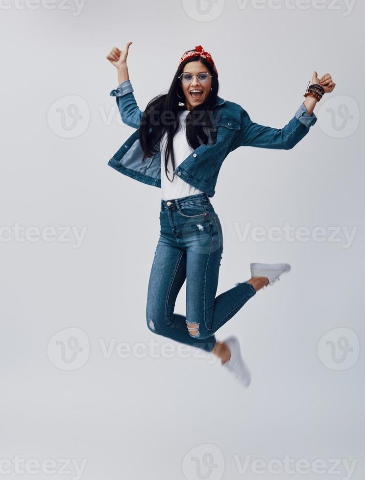 Full length of attractive young woman in bandana smiling while hovering against grey background photo