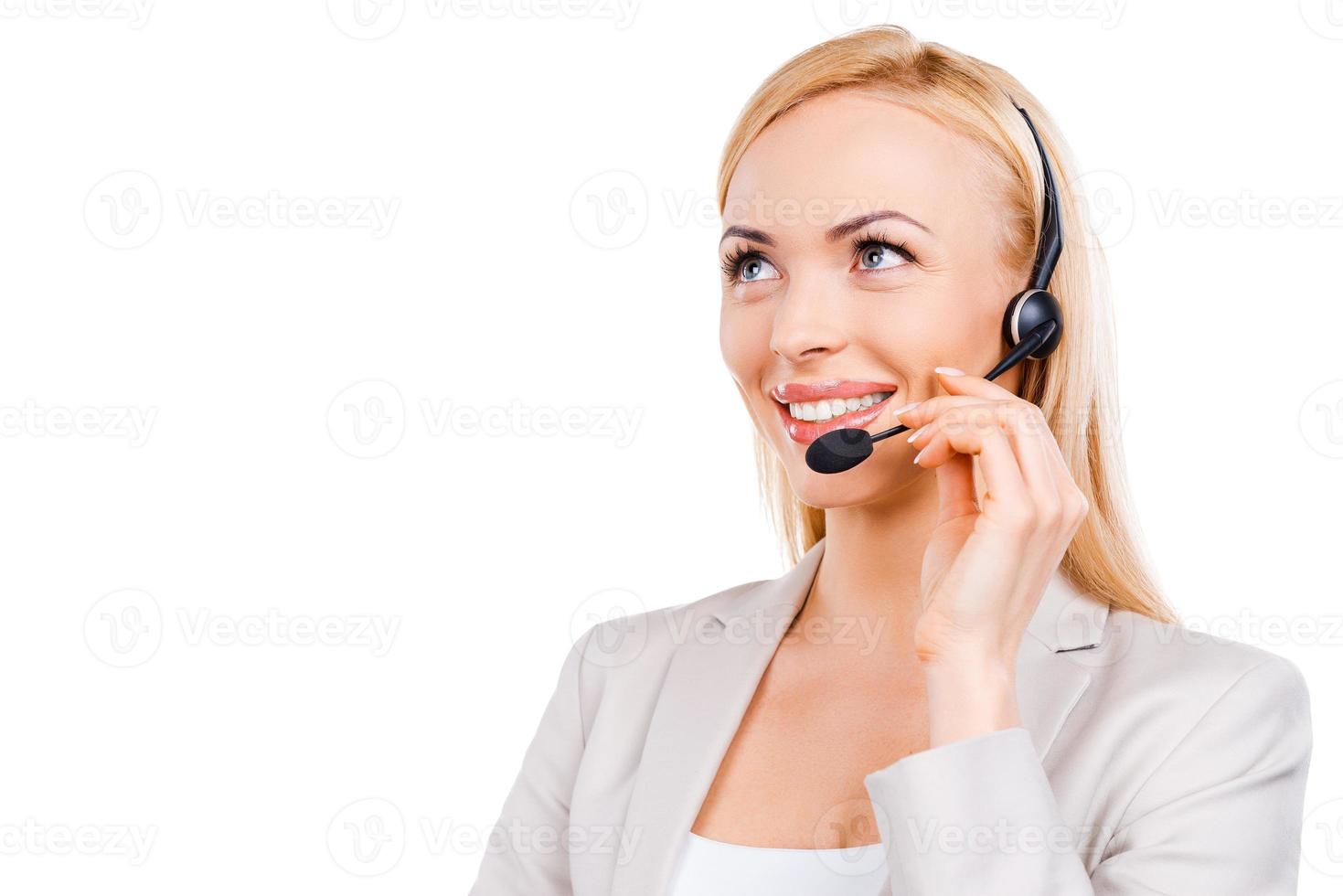 Operator at work. Confident mature customer service representative adjusting her headset and smiling while standing against white background photo