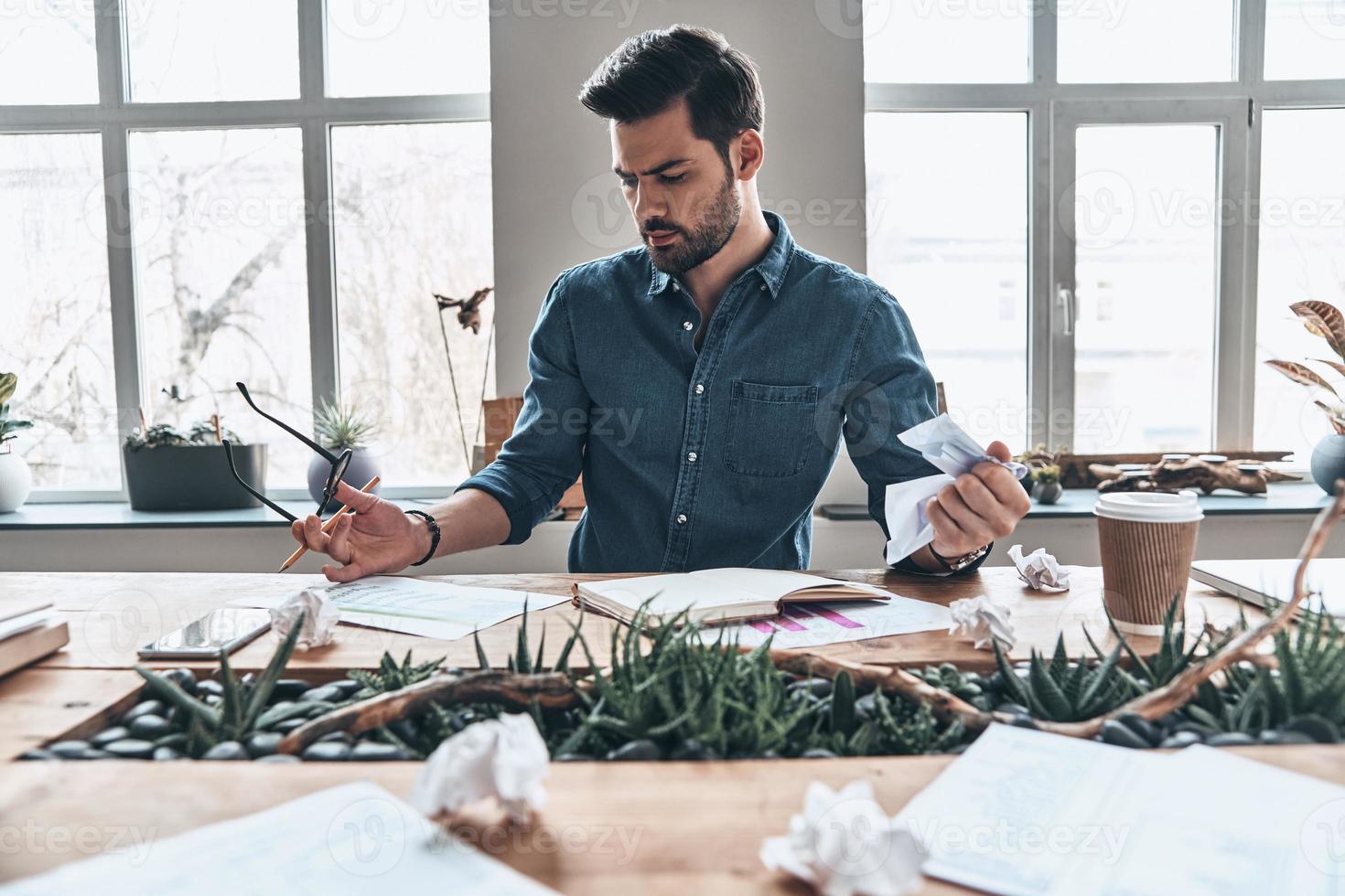 Searching for inspiration. Handsome young man working and crumpling paper  while sitting in the office 13503426 Stock Photo at Vecteezy