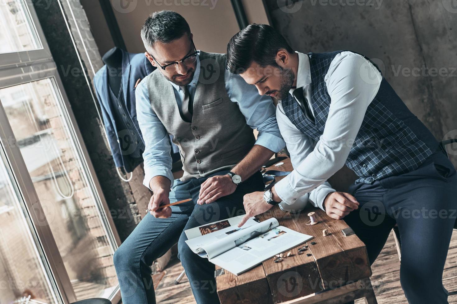 Searching for fashion muse. Handsome young man choosing design with his client while spending time in the workshop photo