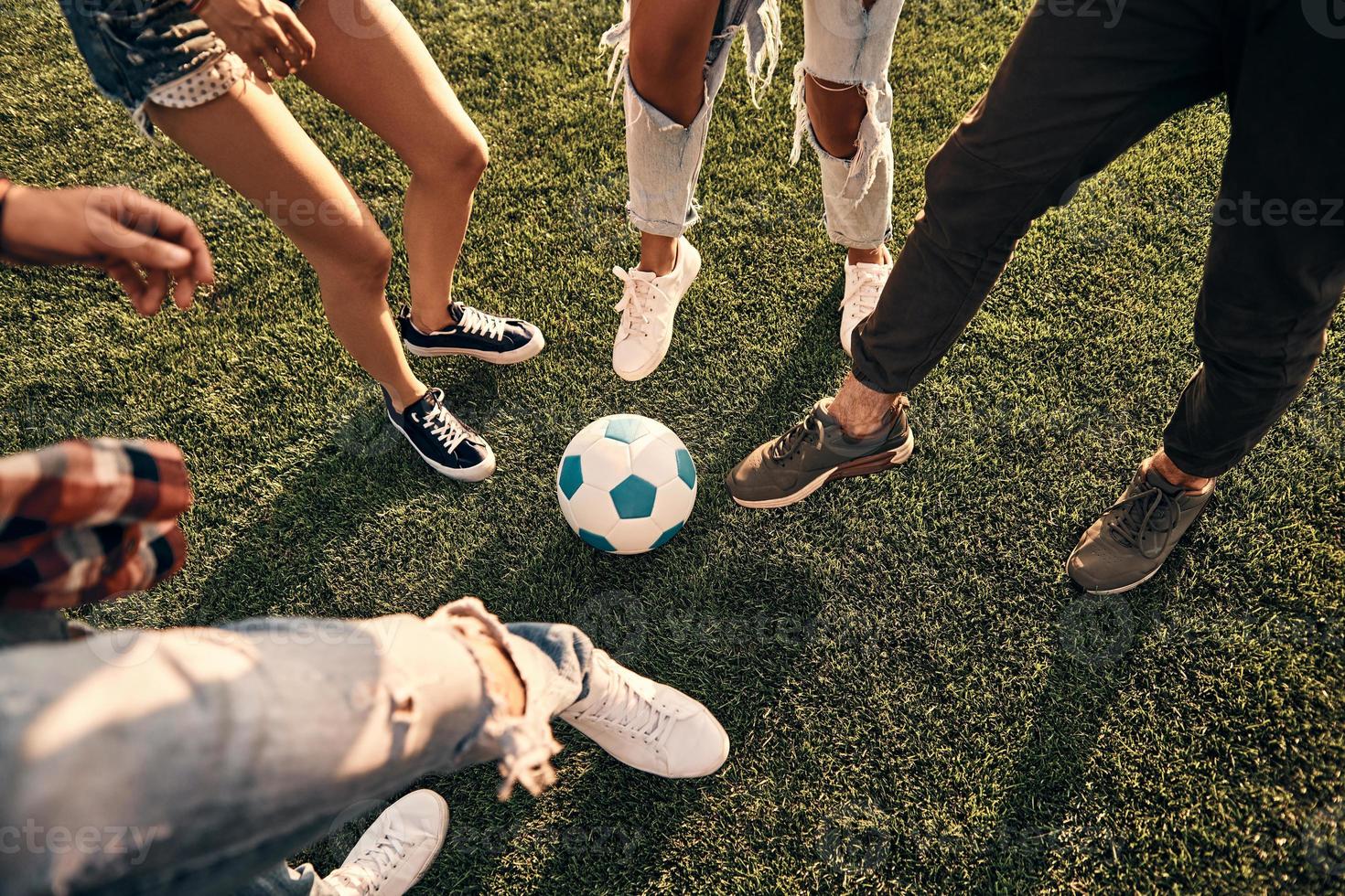 Close-up of young people in casual wear playing soccer while spending time outdoors photo