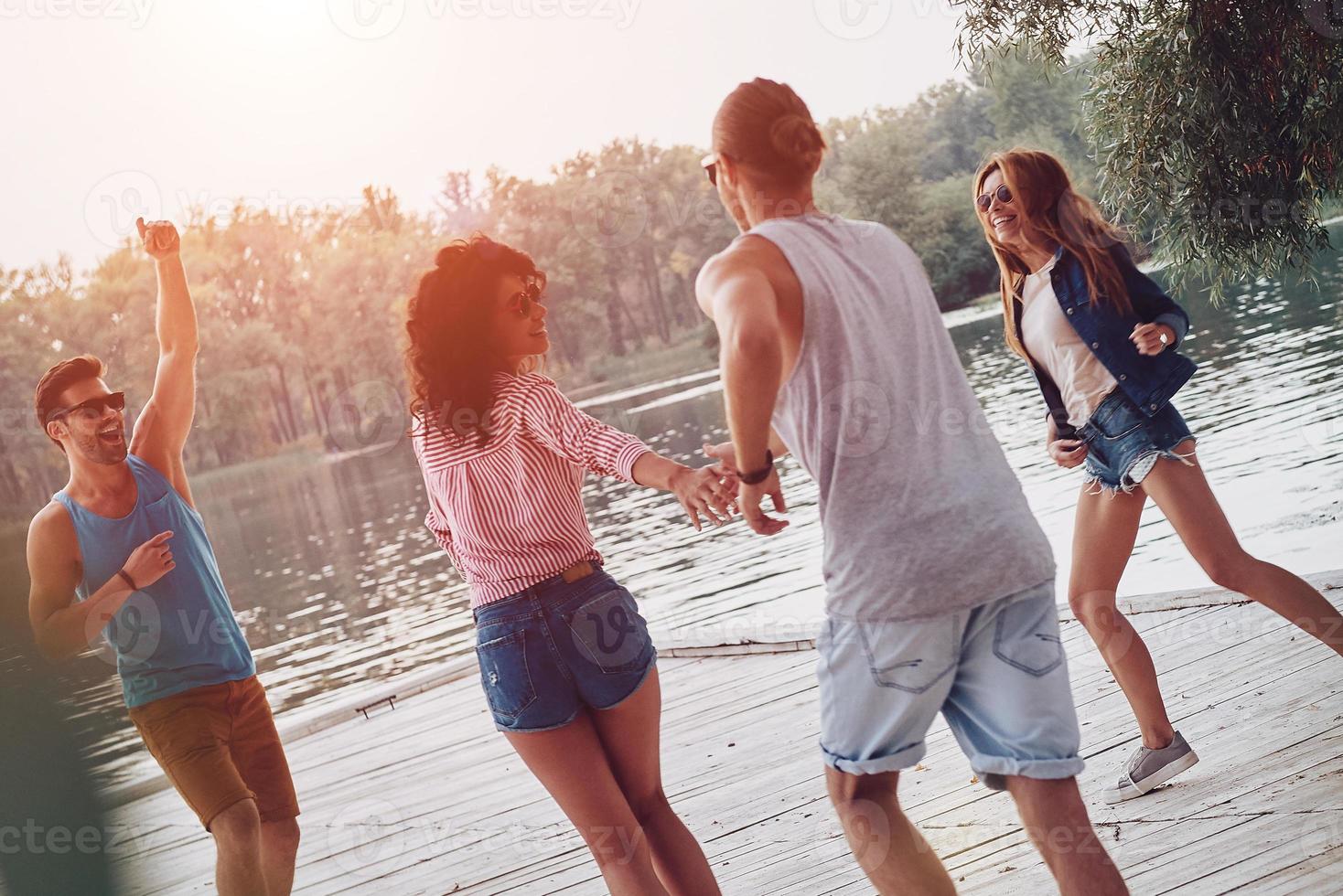 Going crazy. Full length of young people in casual wear smiling and having fun while standing on the pier photo