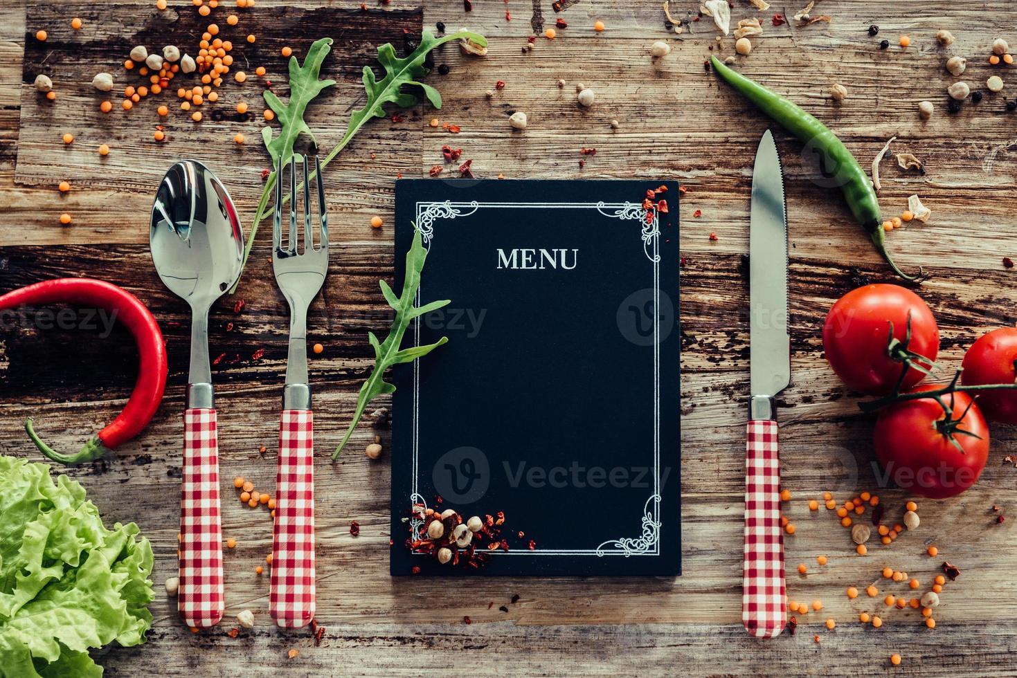 Restaurant menu. Top view of chalkboard menu laying on the rustic wooden desk with vegetables around photo