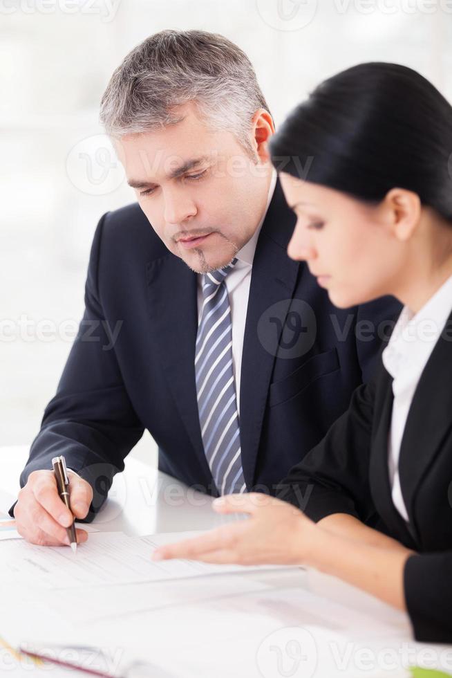 Working on project together. Two confident business people discussing something while sitting together at the table photo