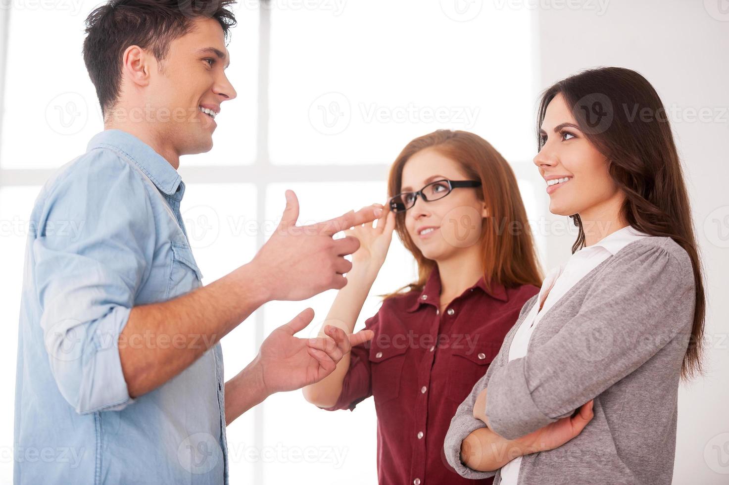 Friendly talk. Discussing a good condition contract. Two beautiful young women discussing document while two men communicating on background photo