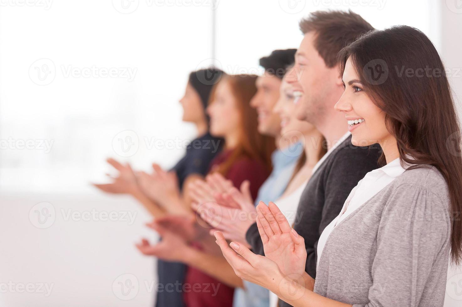 gente aplaudiendo. vista lateral de un grupo de jóvenes alegres parados en fila y aplaudiendo a alguien foto