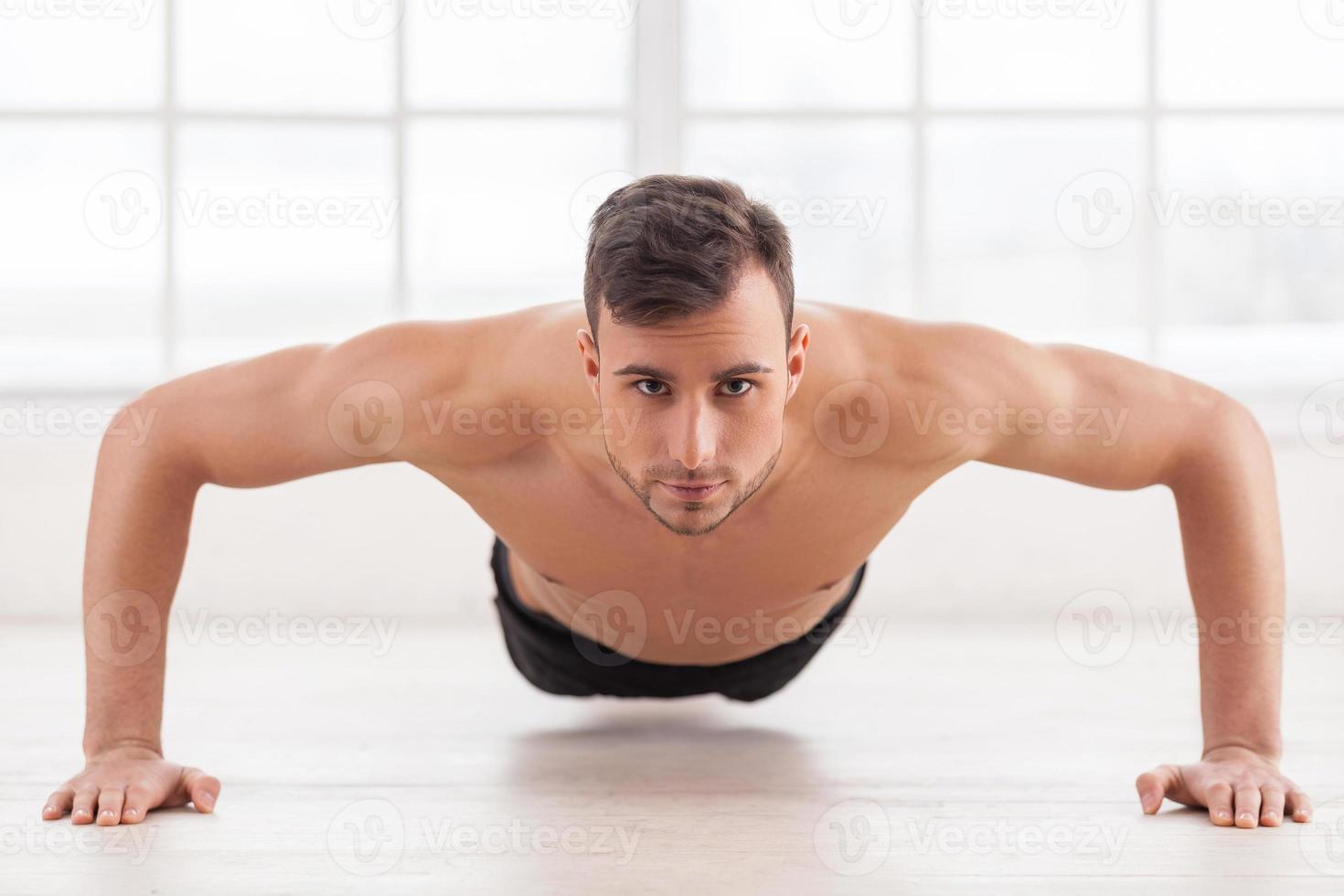 Push-ups. Young muscular man doing push-ups and looking at camera photo