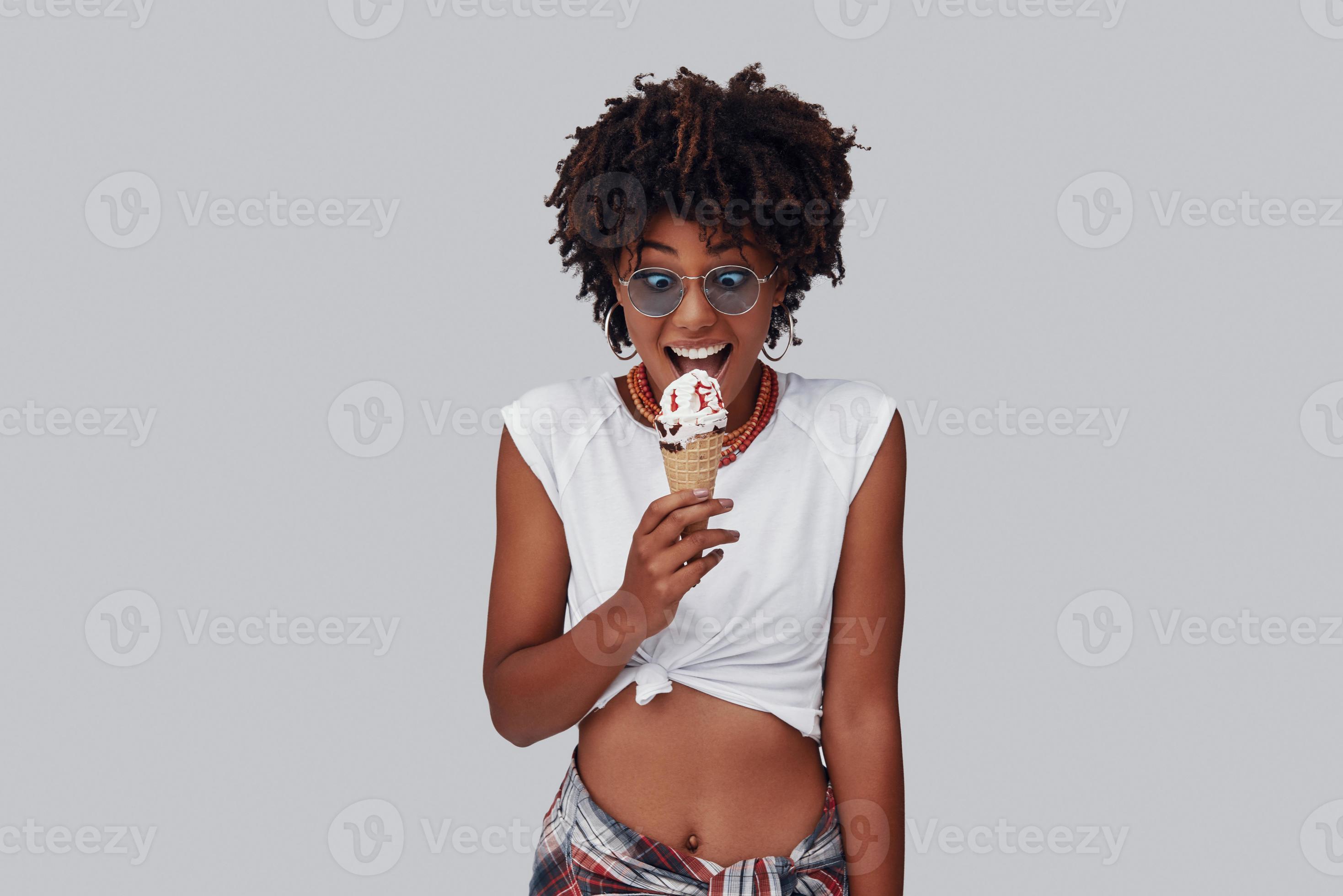 Attractive young African woman eating ice cream and smiling while