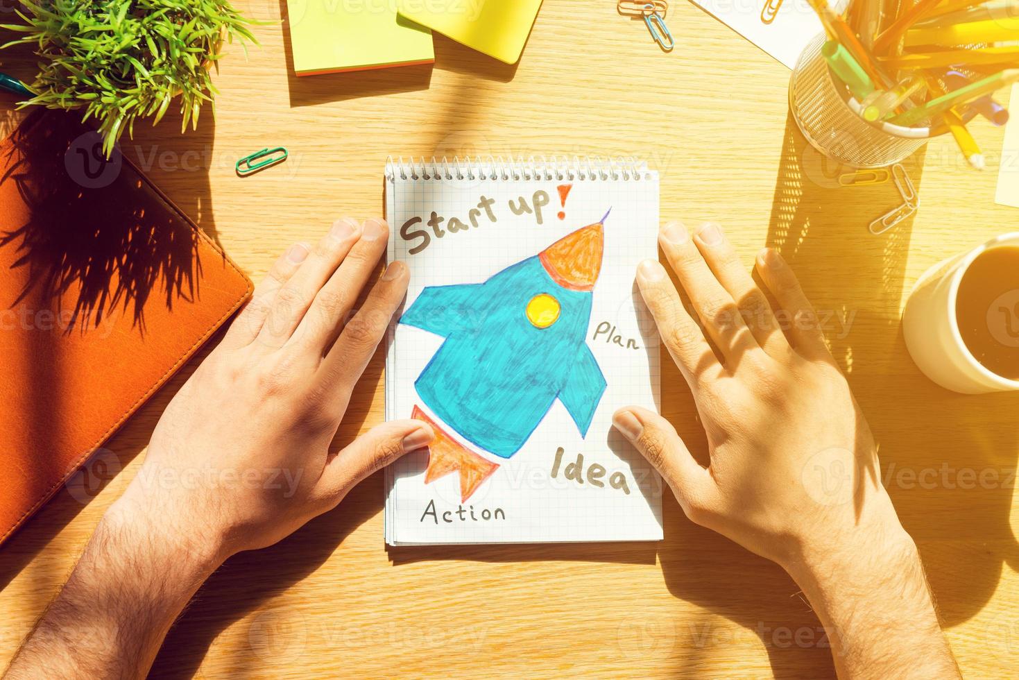 Start up. Close-up top view of man holding hands on paper with sketch laying on the wooden desk photo