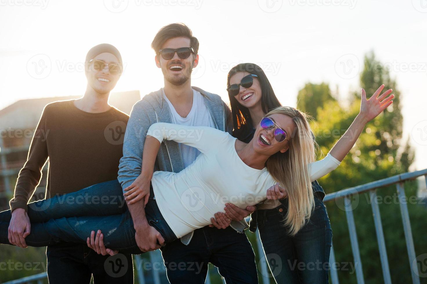 Just having fun. Group of cheerful young people having fun and looking at camera while standing outdoors  together photo