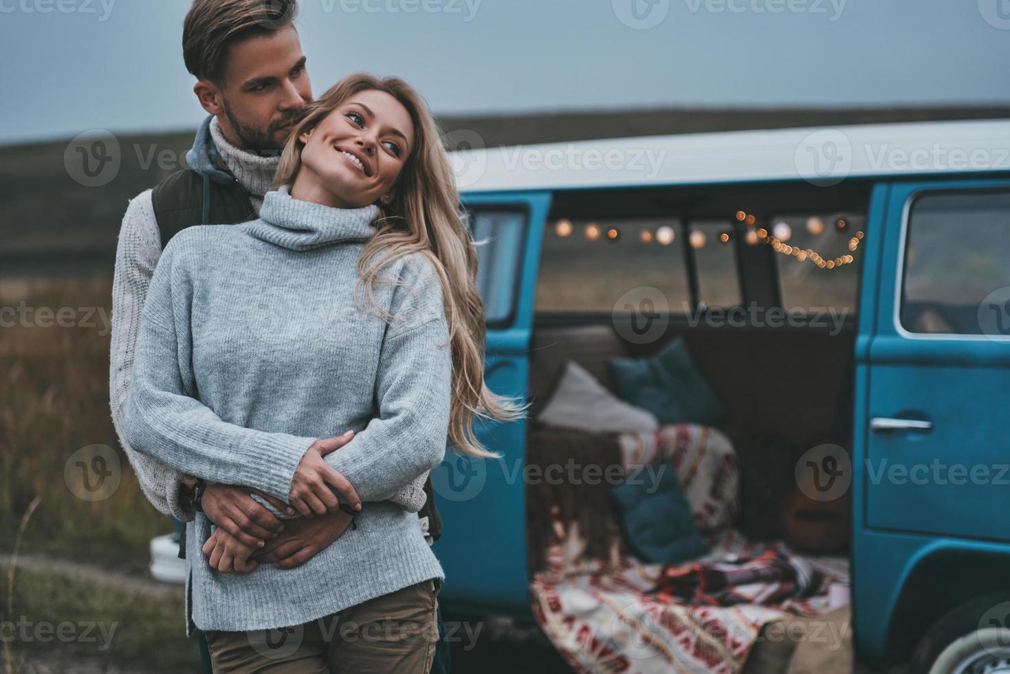 Calm and relaxed.  Handsome young man embracing his attractive girlfriend while enjoying their road travel photo