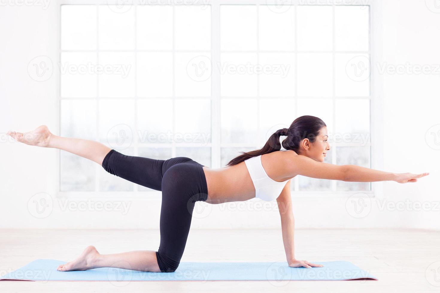 entrenamiento deportivo vista lateral de una hermosa joven india entrenando en una alfombra de yoga foto