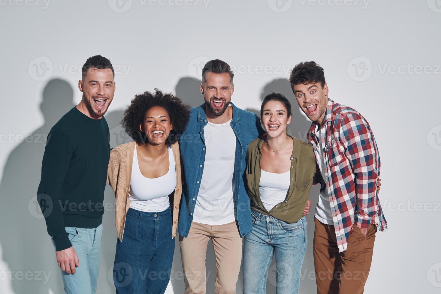 grupo de jóvenes hermosos con ropa informal que se unen y sonríen mientras  se enfrentan a un fondo gris 13504794 Foto de stock en Vecteezy