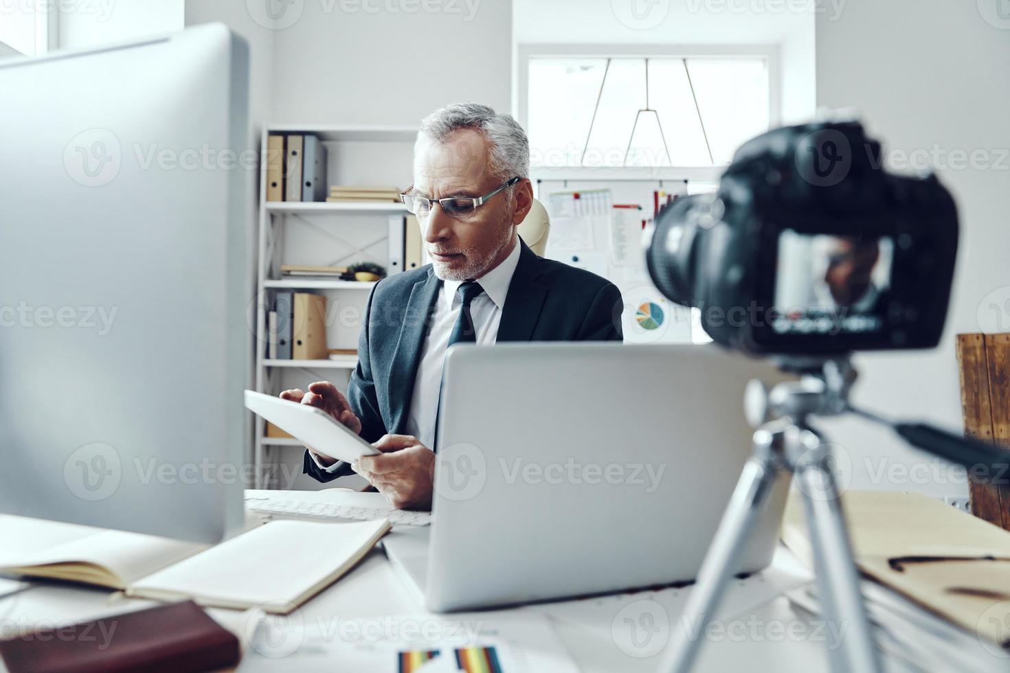 hombre mayor con elegante traje de negocios que usa tecnologías modernas mientras hace videos en las redes sociales foto