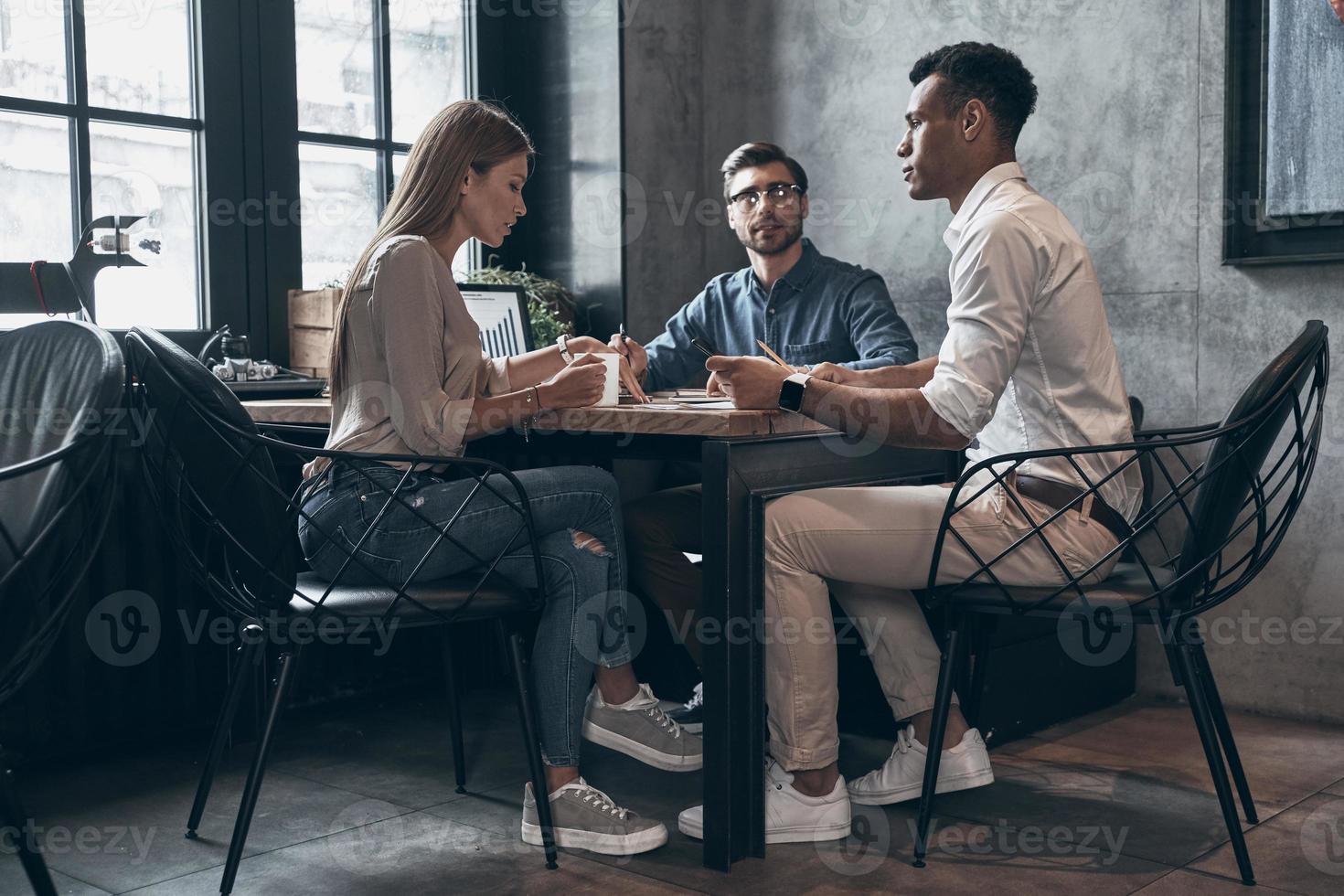 Group of young people in smart casual wear discussing business while working in office photo