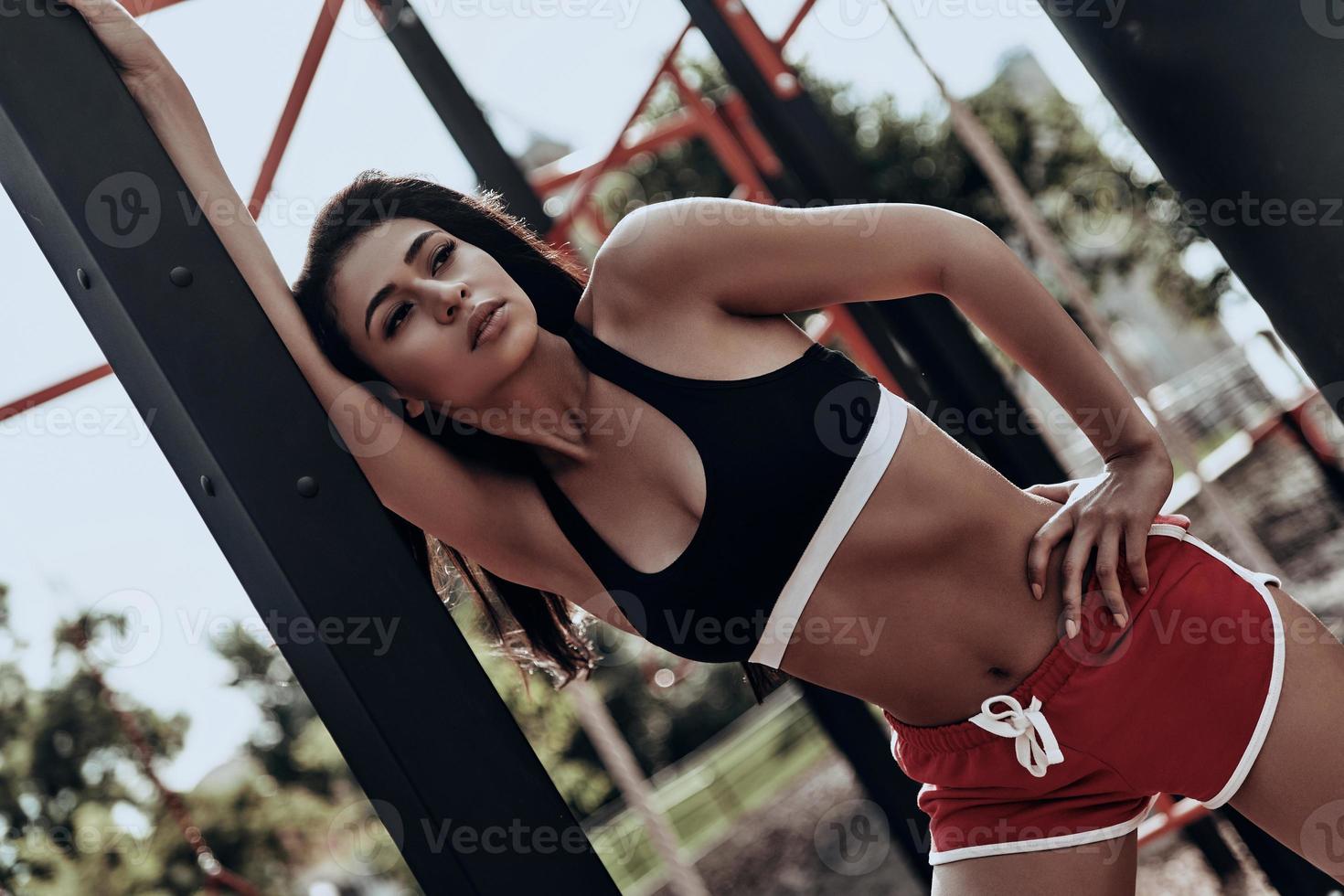 Naturally beautiful.  Attractive young woman in sport clothing keeping hand on hip and looking away while standing outdoors photo