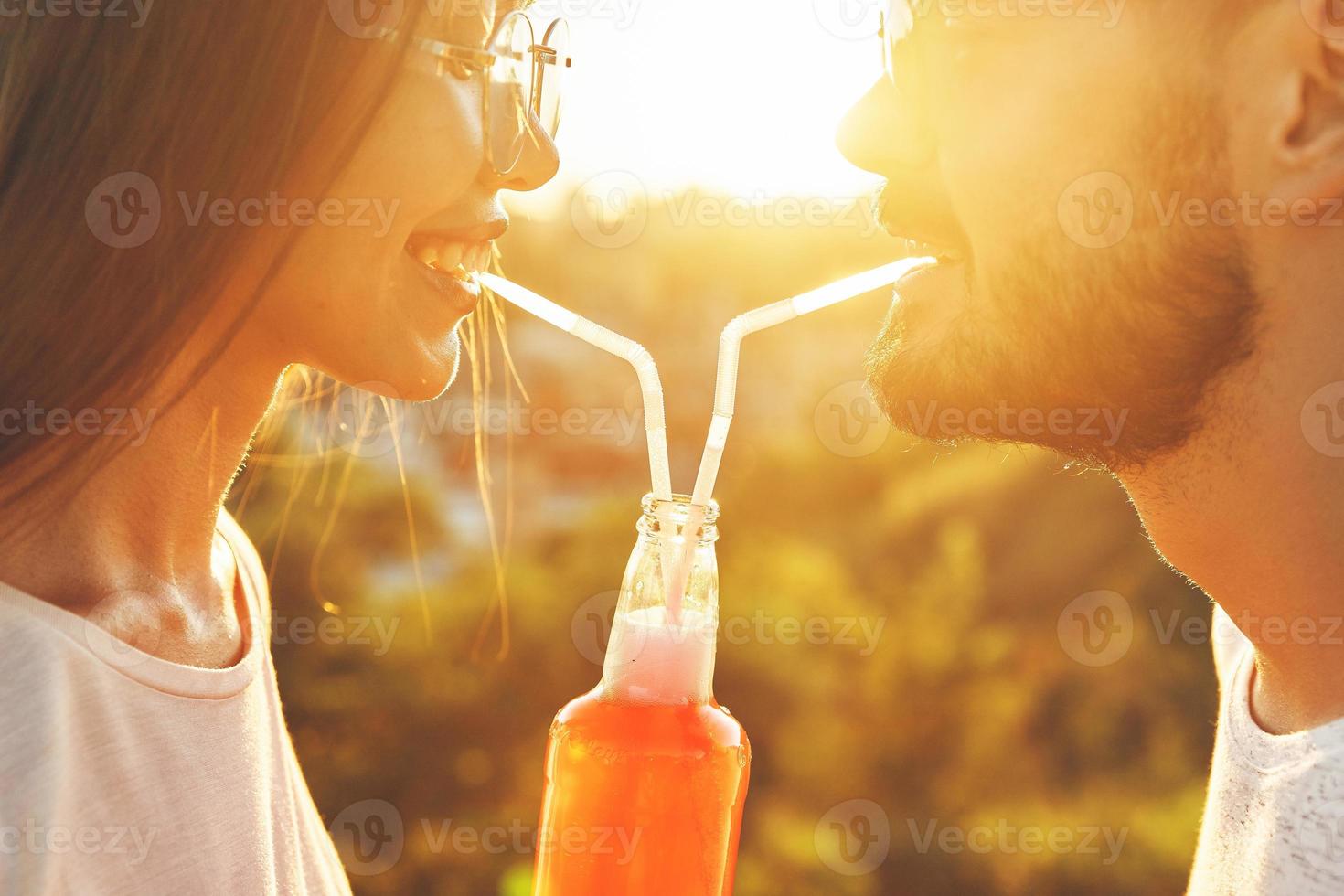 feliz pareja joven bebiendo de una botella con pajitas foto