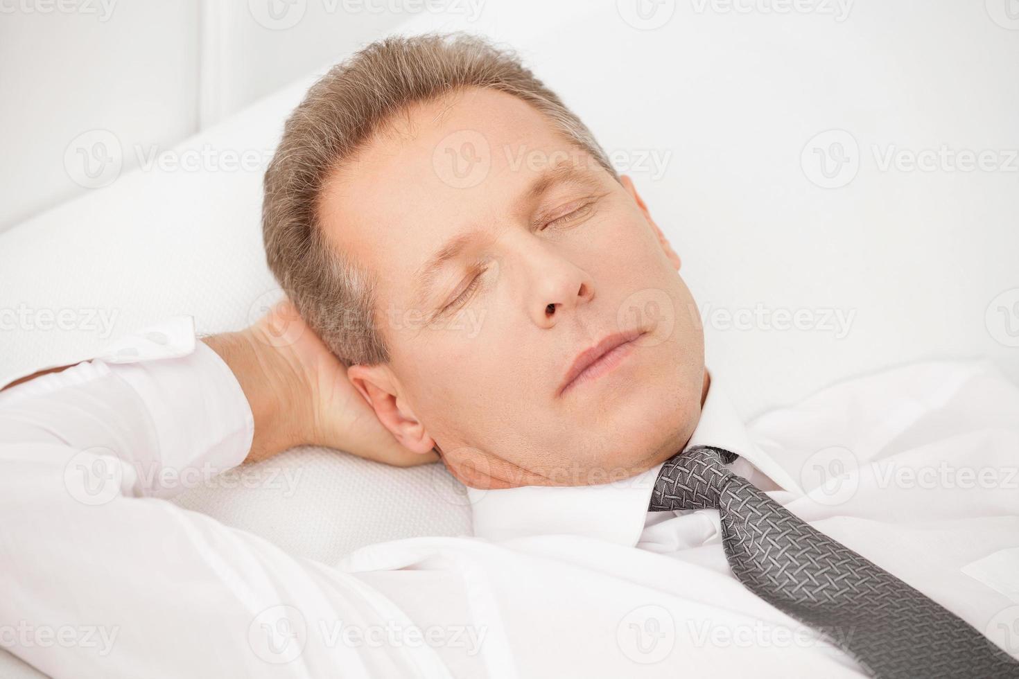 Sleeping businessman. Tired grey hair man in shirt and tie lying on bed and keeping eyes closed photo