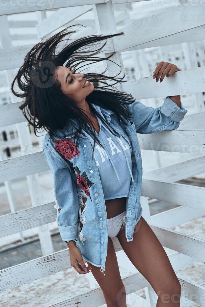 Beauty in motion.  Attractive young mixed race woman in jeans shirt shaking her head and smiling while standing outdoors photo