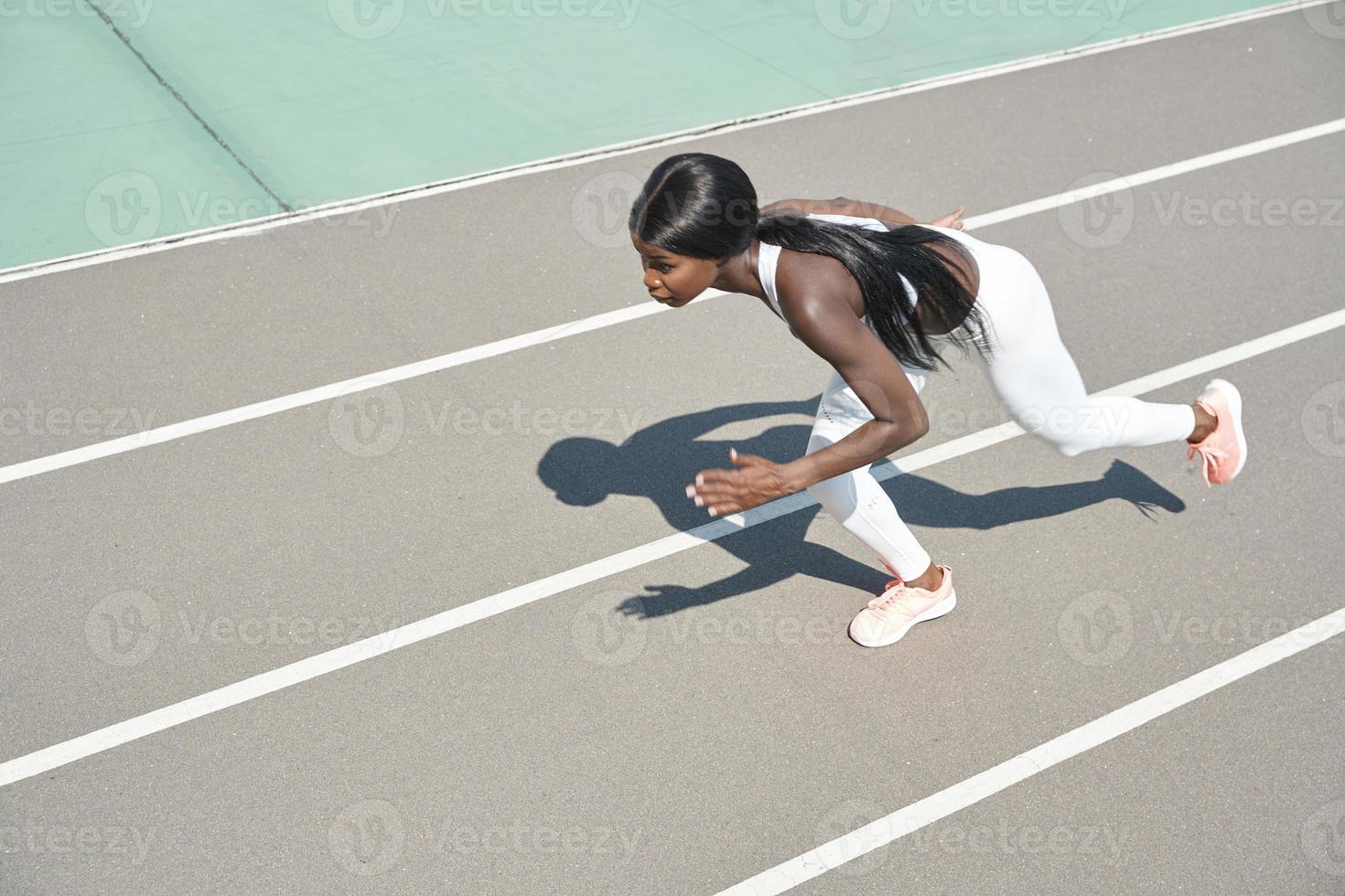 vista superior de una hermosa joven africana con ropa deportiva corriendo en la pista al aire libre foto