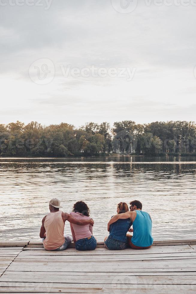 mejor lugar para descansar. hermosas parejas jóvenes abrazándose mientras se sientan en el muelle foto