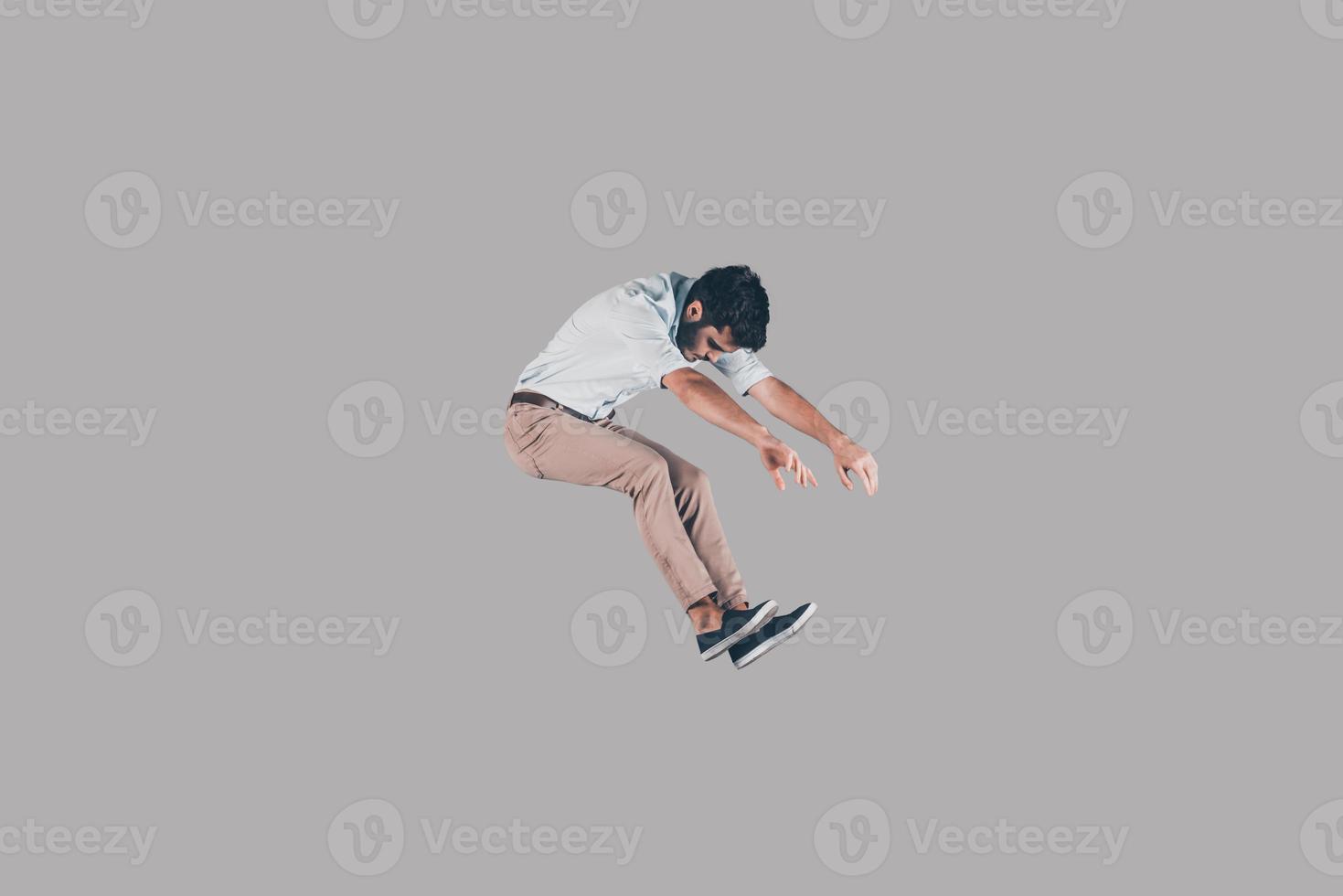 en el aire. tiro en el aire de un joven apuesto saltando y gesticulando contra el fondo foto