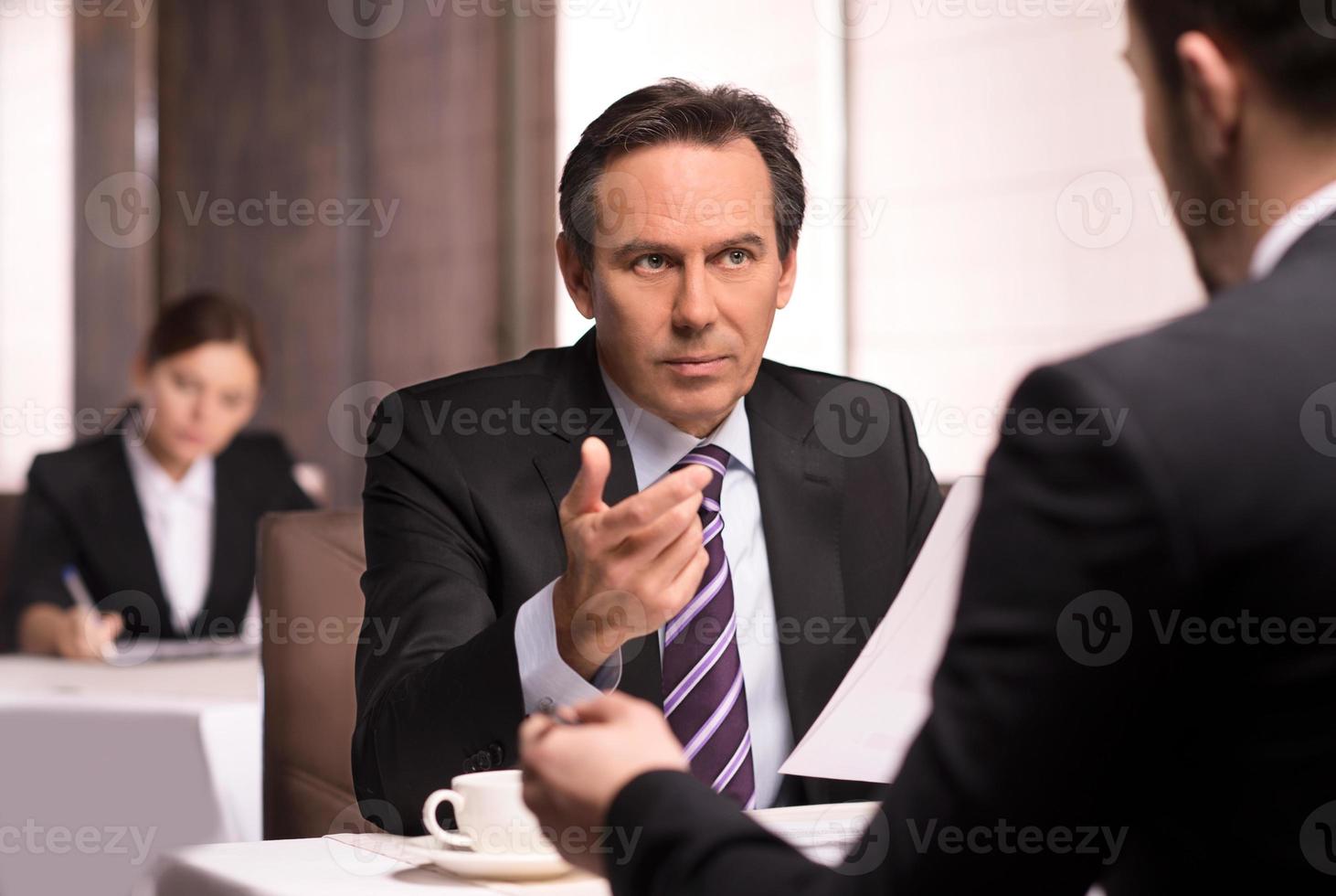 Business people at the restaurant. Business people in formalwear discussing something while sitting at the restaurant photo