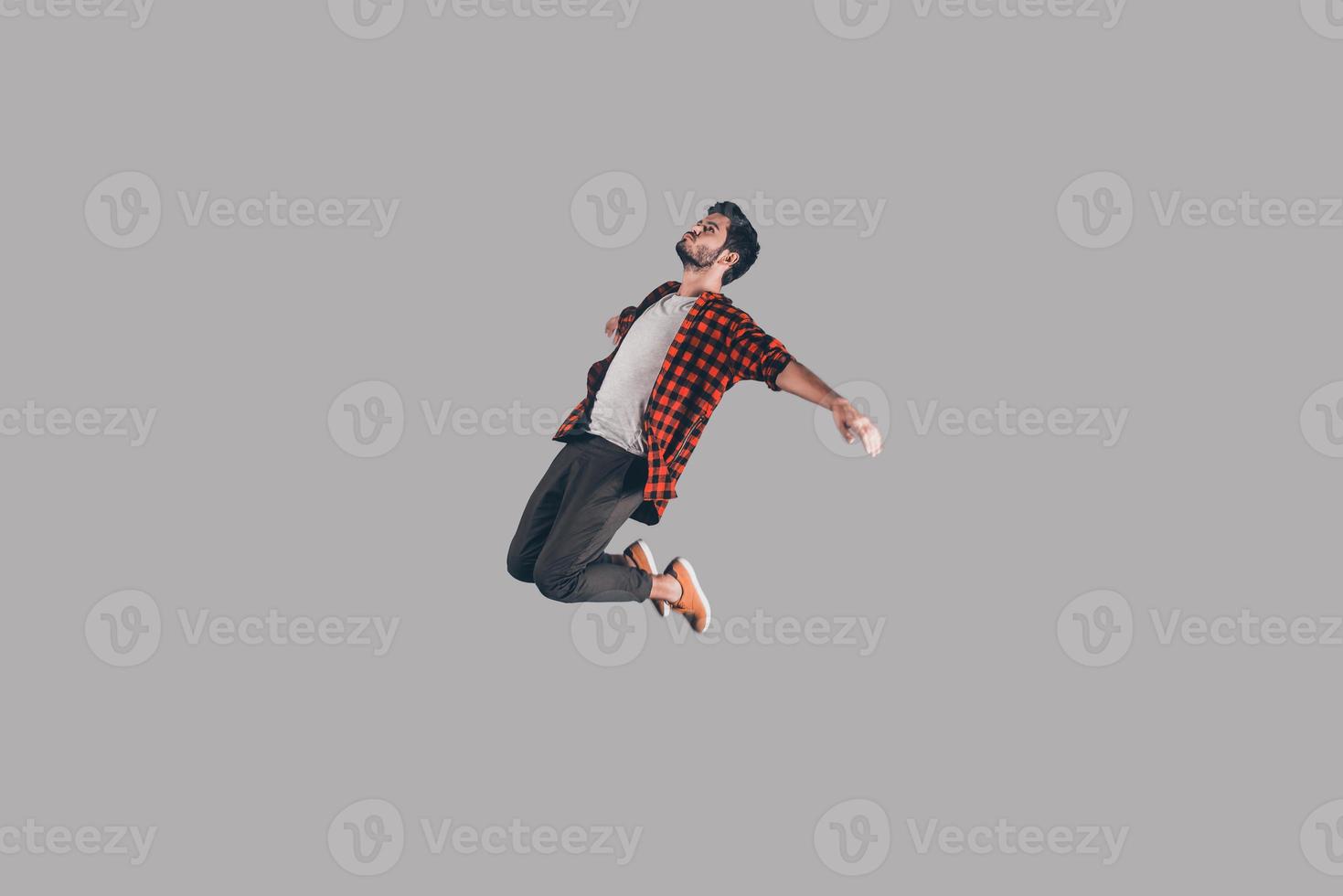 Free falling. Mid-air shot of handsome young man jumping and gesturing against background photo