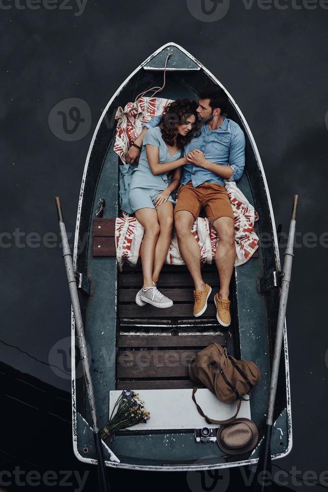 pareja amorosa. vista superior de una hermosa pareja joven abrazándose y sonriendo mientras yacía en el bote foto