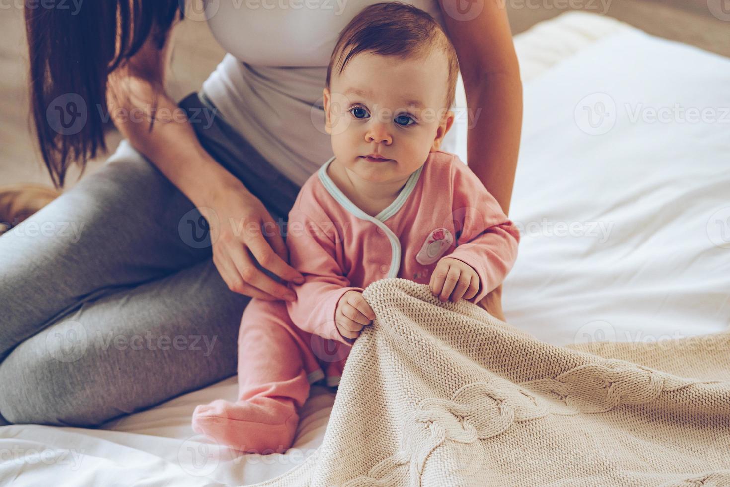 Time to start new day Closeup part of little baby girl sitting on bed with her mother and
