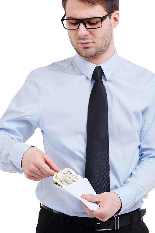 Taking bribe. Young man in shirt and tie taking money from the envelope while standing isolated on white photo