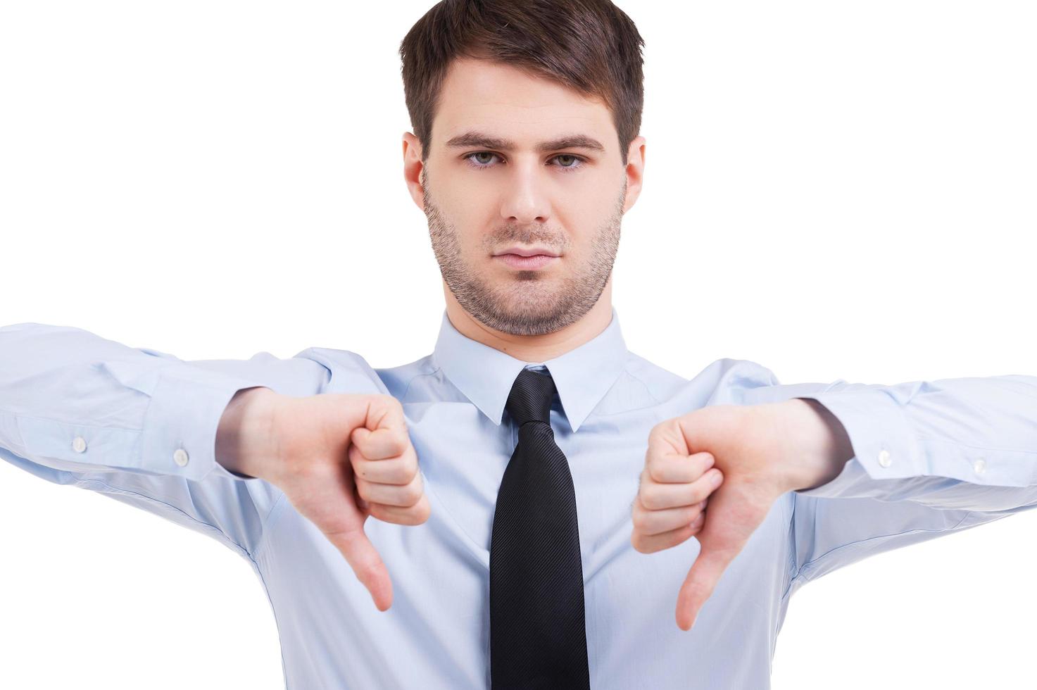 Rejected. Confident young man in shirt and tie looking at camera and showing his thumbs down while standing isolated on white photo