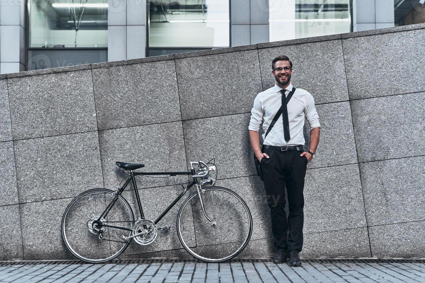 Modern businessman. Good looking young man in full suit looking at camera and smiling while standing outdoors photo