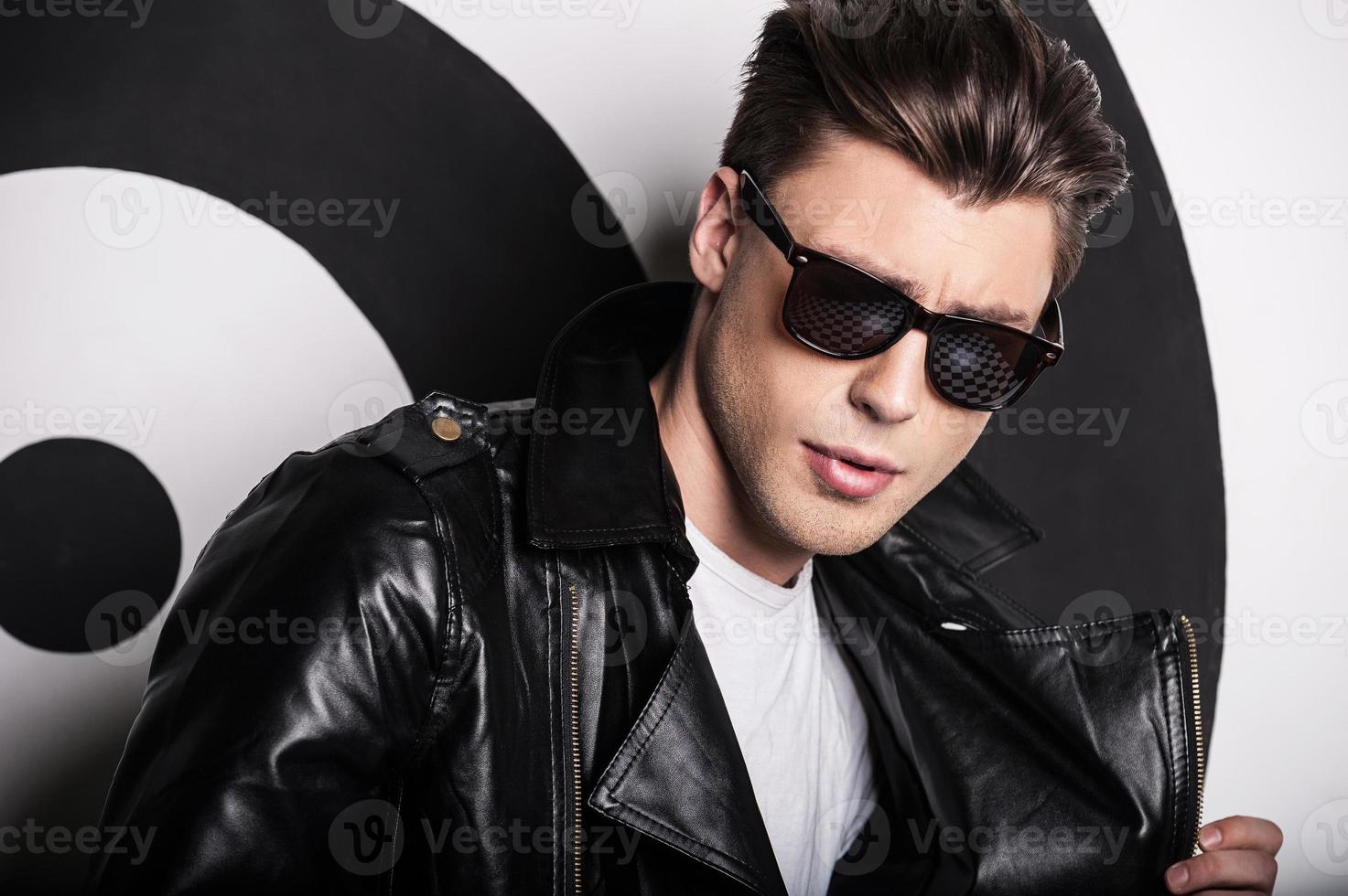 Trendy handsome. Handsome male model in leather jacket posing against target background photo