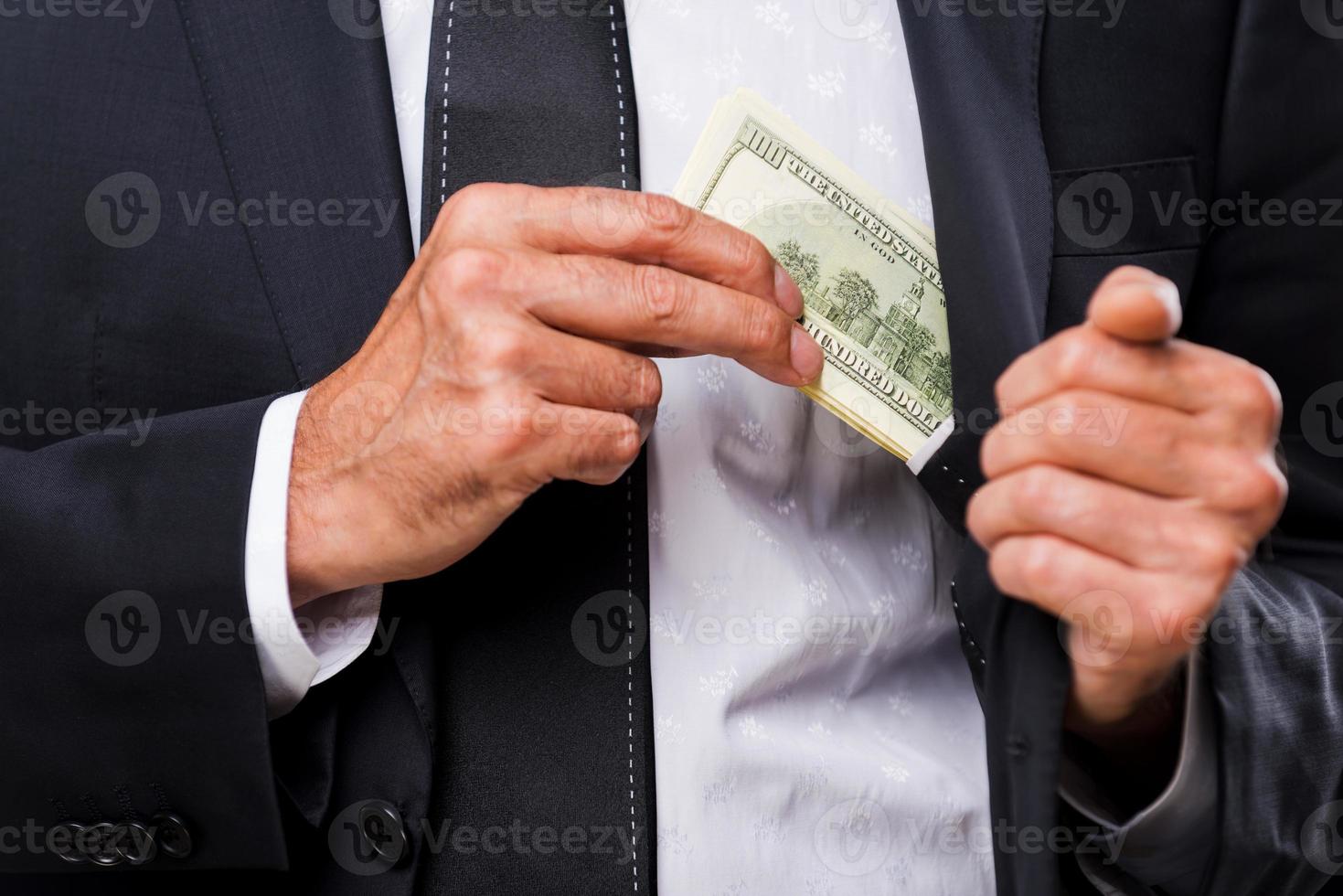 Bribe. Close-up of businessmen hiding money to his pocket photo