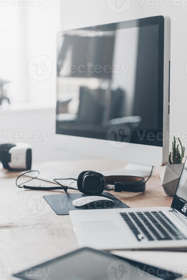 equipamiento innovador. auriculares colocados en el escritorio de la oficina y cerca de la computadora portátil y la computadora foto