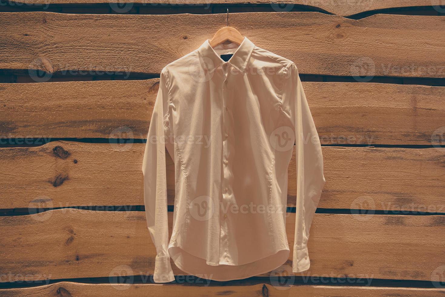 Shirt on the wall. White shirt hanging on the rough wooden wall photo