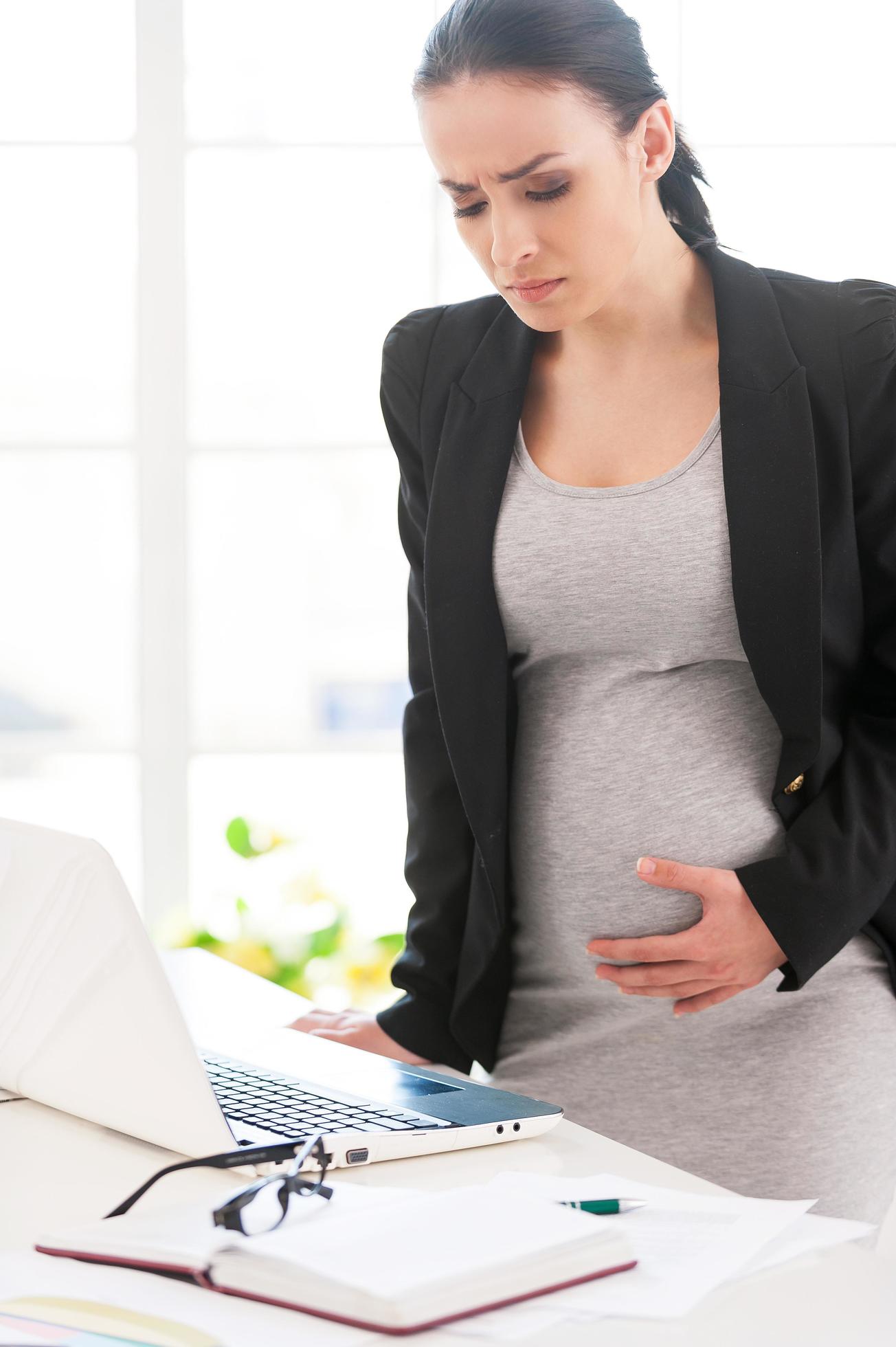 Pregnancy pains and aches. Depressed pregnant businesswoman touching