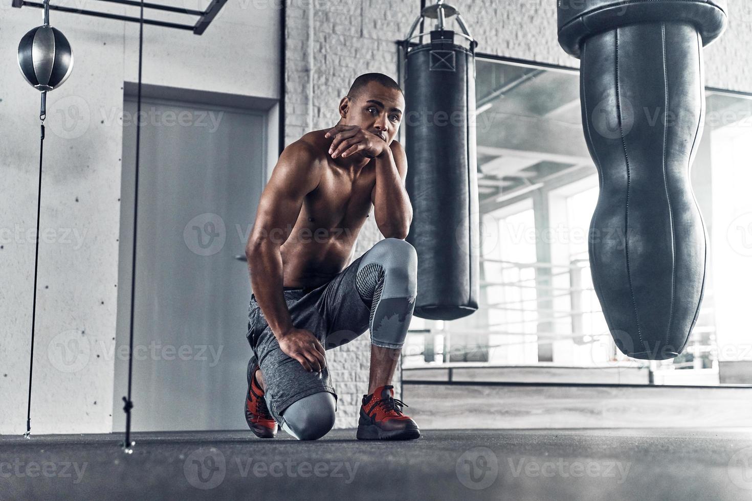 About to do another exercise. Shirtless young African man looking away while spending time in the gym photo