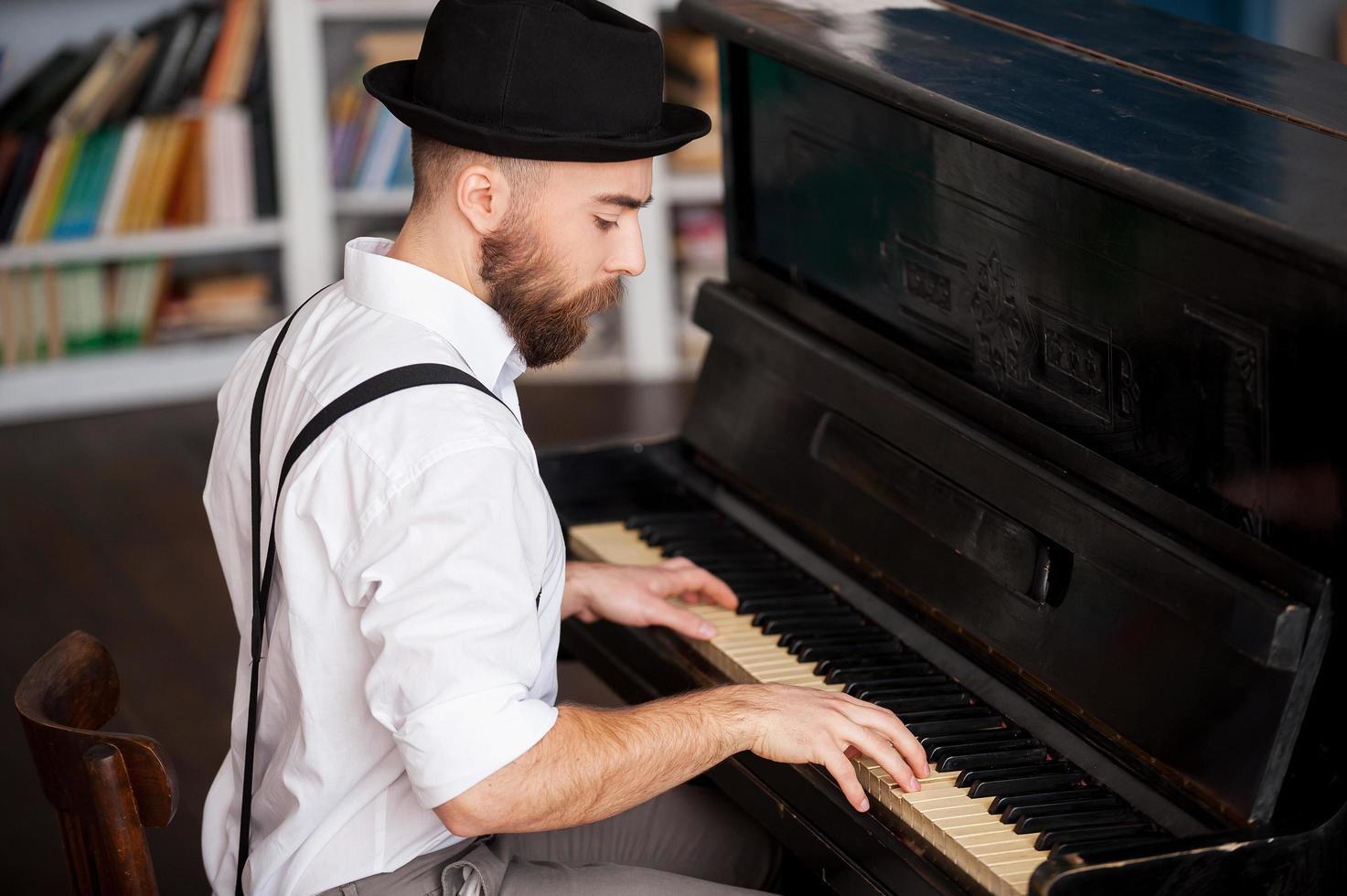 Making music. Profile of a handsome young bearded men playing piano photo