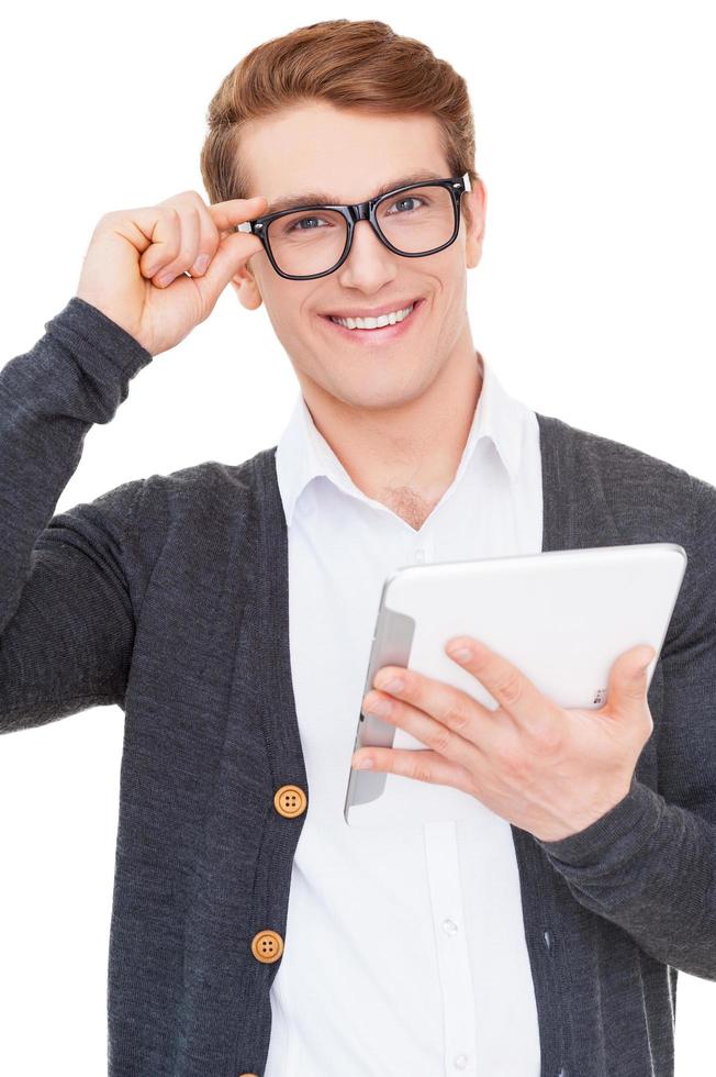Confident in his gadget. Handsome young man holding digital tablet and smiling while standing isolated on white photo