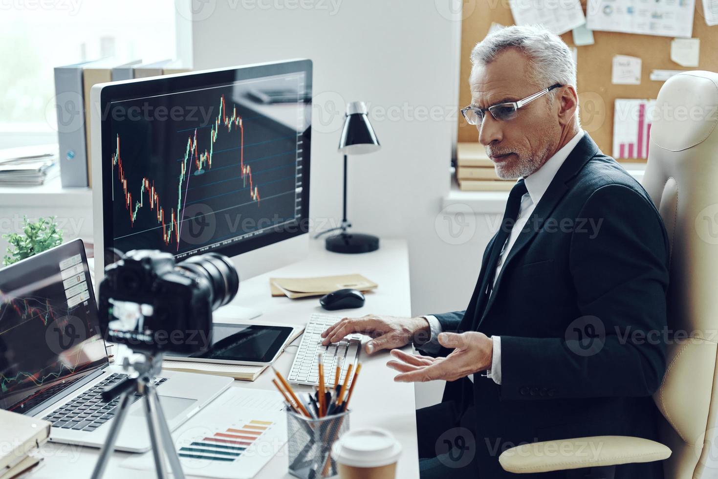 Senior man in elegant business suit using modern technologies while making social media video photo