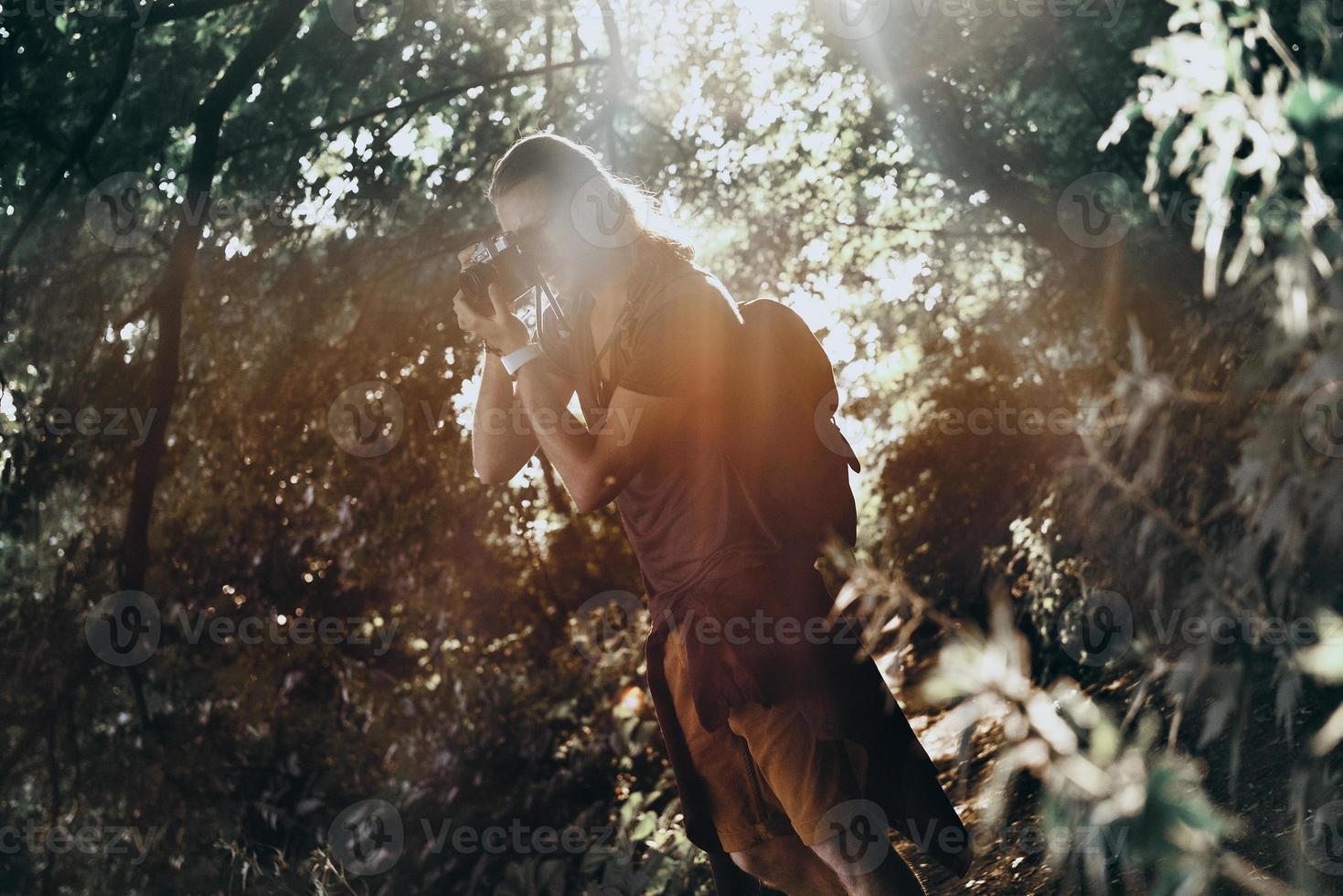 In the amazing place. Young man in casual clothing photographing something while standing outdoors photo