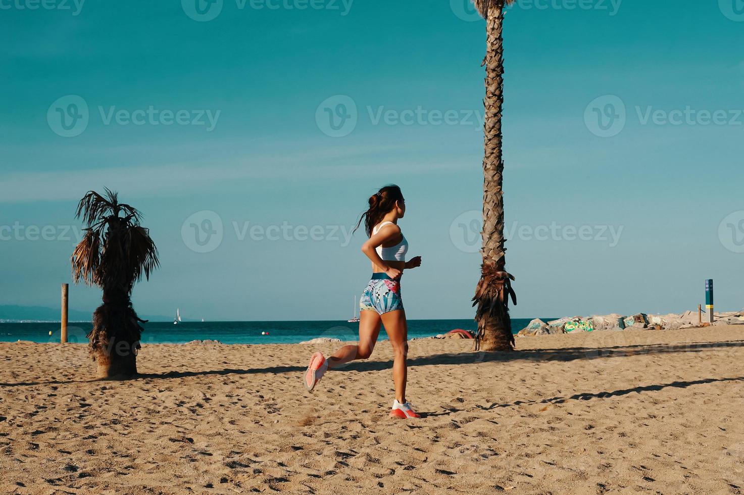 Towards a healthier lifestyle. Full length of beautiful young woman in sports clothing jogging while exercising outdoors photo