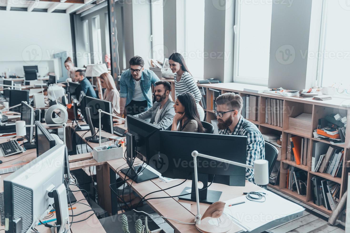 inspirado para lograr los mejores resultados. grupo de jóvenes empresarios con ropa informal inteligente que trabajan y se comunican mientras están sentados en el escritorio de la oficina foto