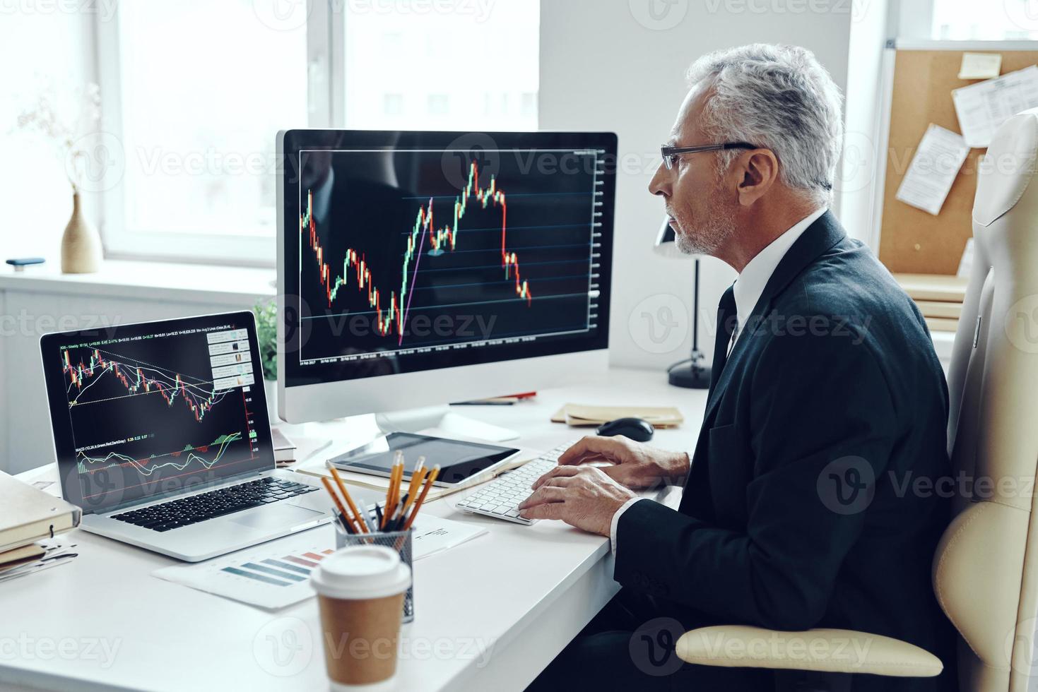 Senior trader in elegant business suit using computer while working at the office photo