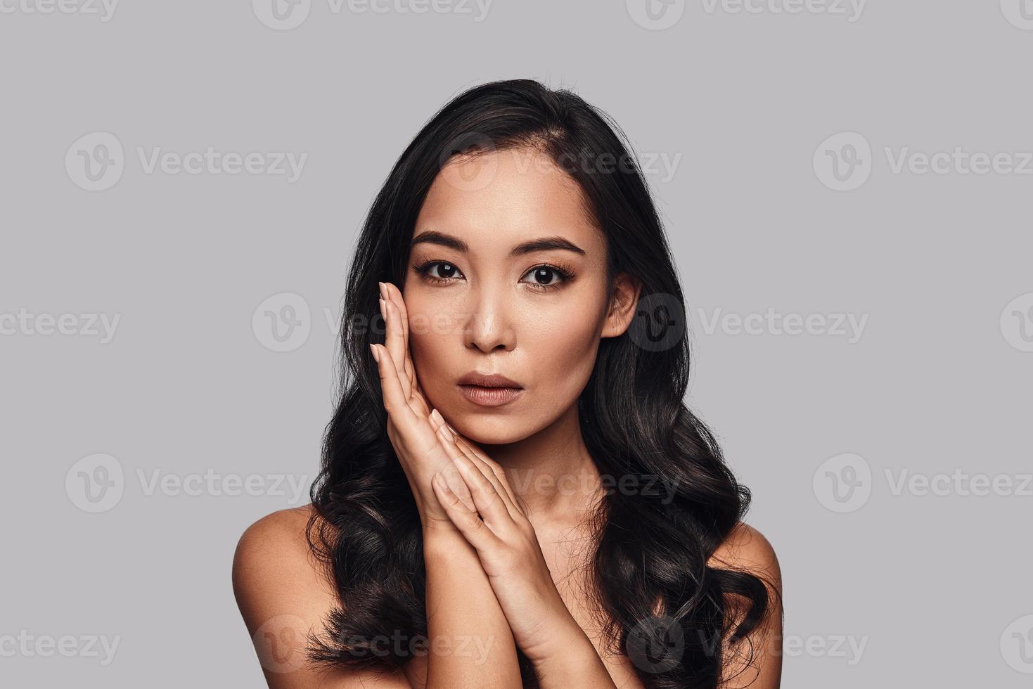 Soft sensuality. Beautiful young woman looking at camera while standing against grey background photo