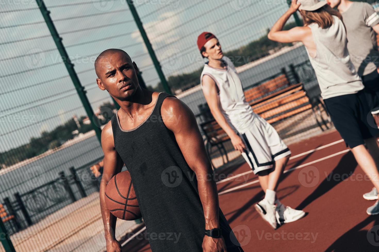 Another break. Young African man in sports clothing looking away while playing basketball outdoors photo